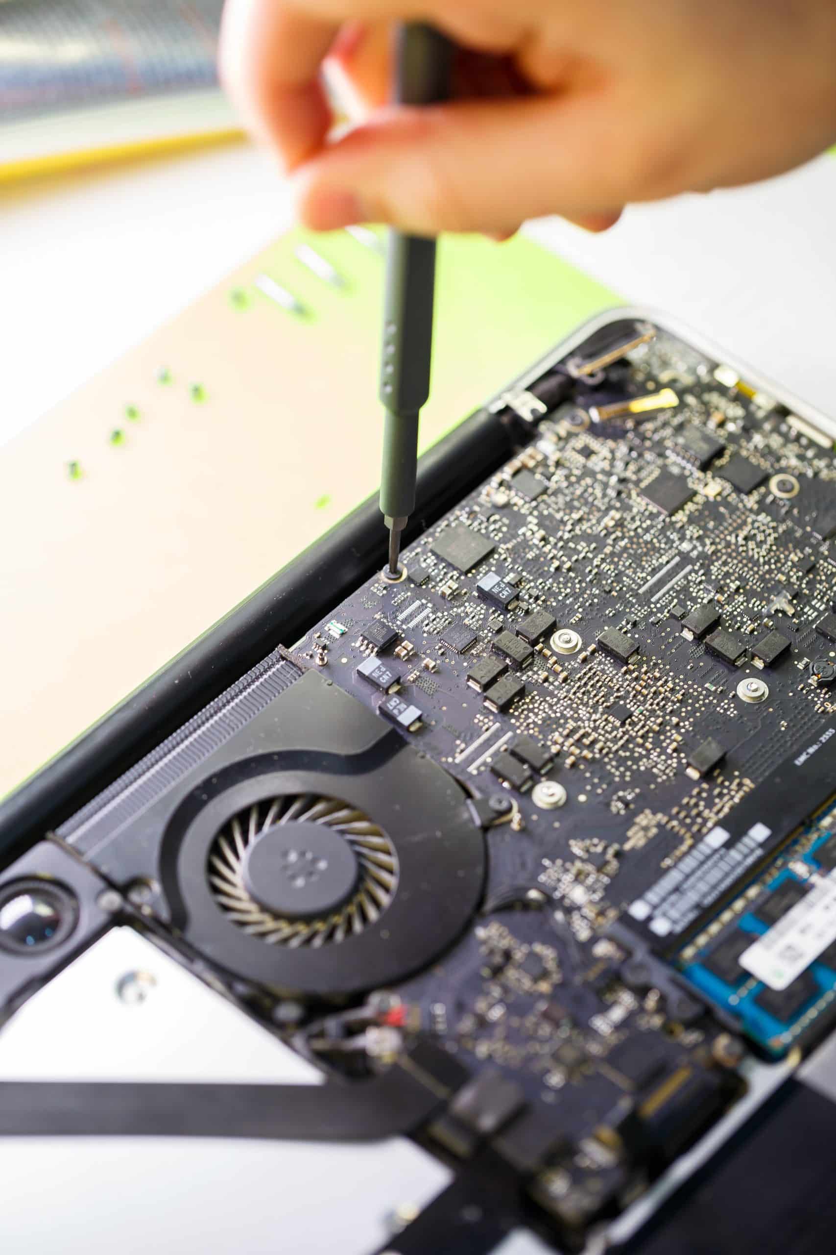 Ein Mann reinigt einen Laptop mit einem Spezialwerkzeug von Staub. Reparatur und Wartung von Laptops und PCs. Werbeanzeigen für Reparaturdienstleistungen im Bereich Elektronik und Geräte.